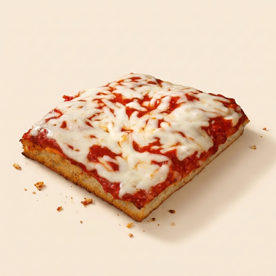 A square slice of pizza with melted white cheese and red tomato sauce, photographed on a clean warm beige background with a few crumbs nearby.